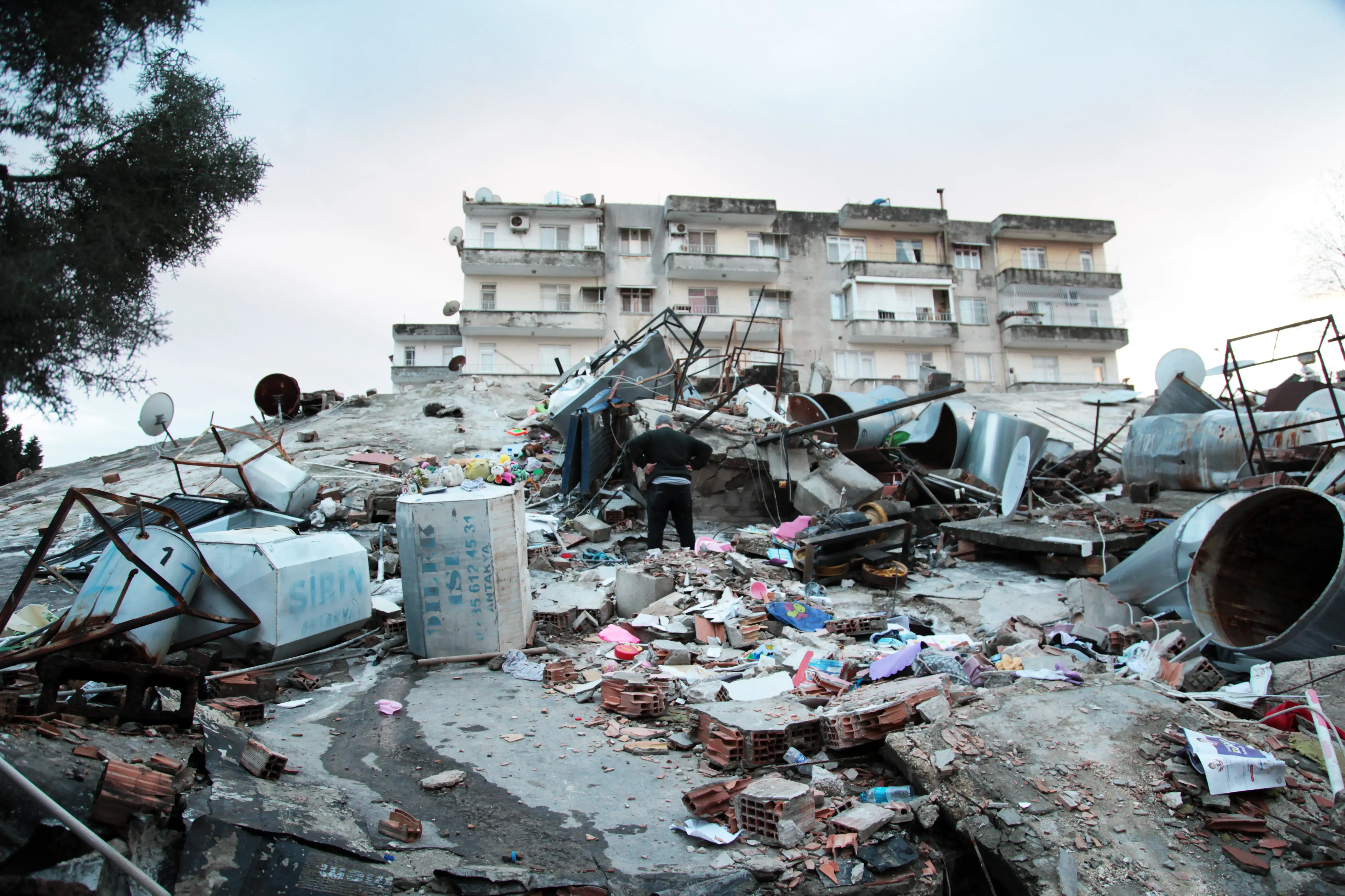 A man stands on top of a collapsed building in Hatay, Türkiye. Photo: Özge Ergin.
